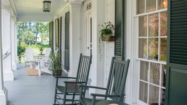 A porch with white columns, green shutters, and a bench. - The Neighbour House B&B (Long Valley)
