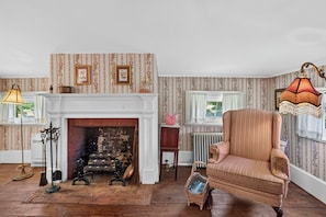 A room with a fireplace, a vintage armchair, and a patterned wallpaper. - The Neighbour House B&B (Long Valley)