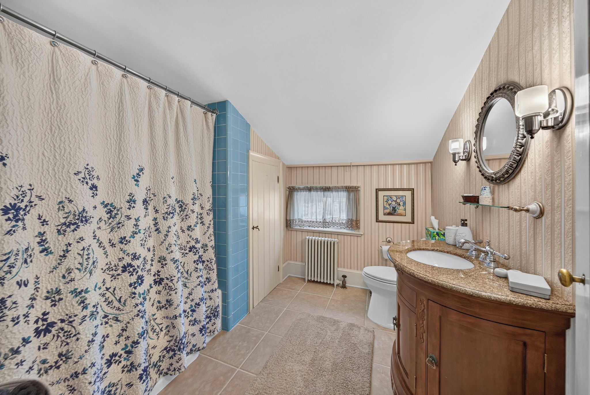 A bathroom with a shower curtain, a toilet, a sink, and a mirror.