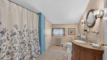 A bathroom with a shower curtain, a toilet, a sink, and a mirror.