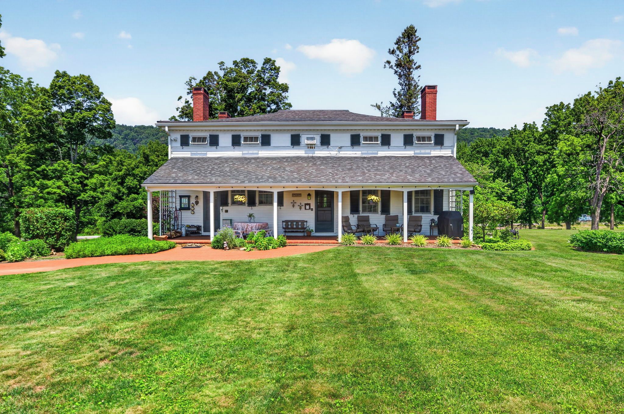 A two-story house with a porch, surrounded by a well-maintained lawn and trees.