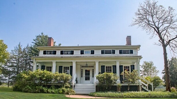 A two-story house with a front porch, columns, and a well-maintained lawn. - The Neighbour House B&B (Long Valley)