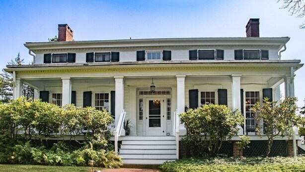 A two-story white building with a central entrance, columns, and a brick pathway leading to the door. - The Neighbour House B&B (Long Valley)