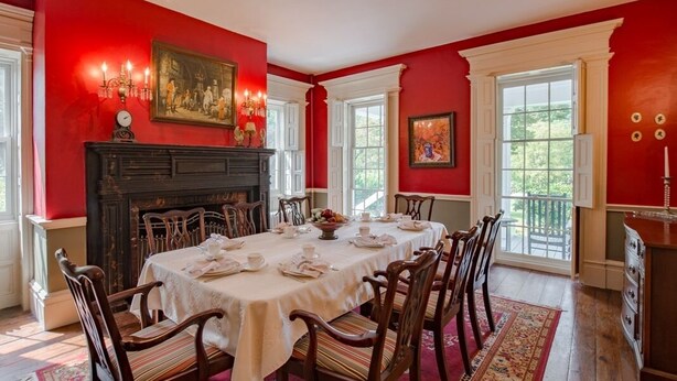 Comedor con una mesa grande dispuesta para seis personas, rodeada de sillas de madera.