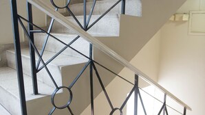 Una escalera con barandilla metálica de diseño geométrico y pasamanos.