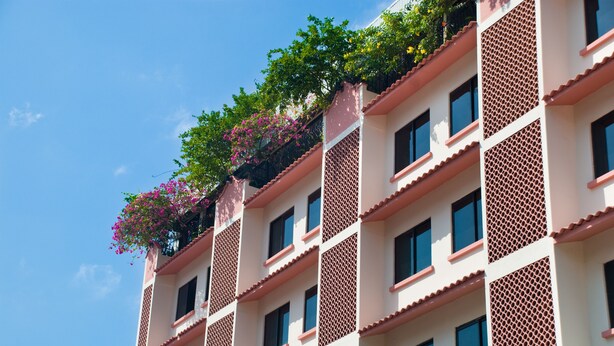 Un edificio de varios pisos con balcones decorados con plantas en flor.