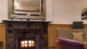 A cozy room with a fireplace, a large mirror, and a comfortable sofa. - Lutwidge Arms Limited (Holmrook)