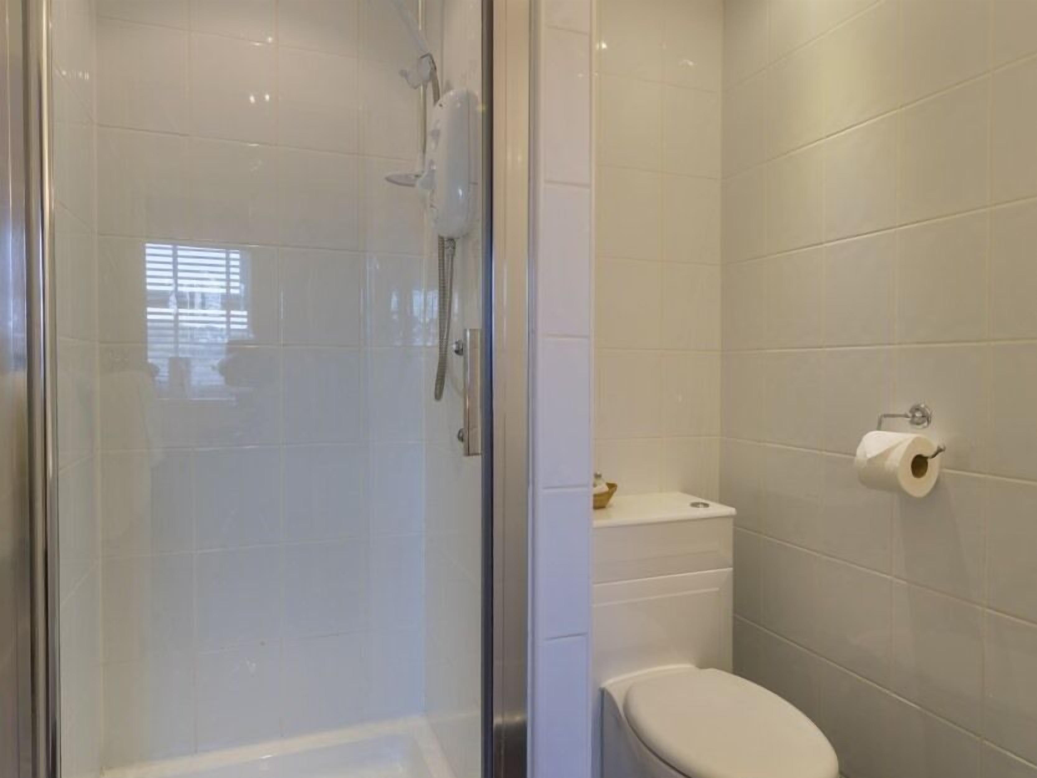 A bathroom with a glass shower enclosure, a toilet, and a towel rack.