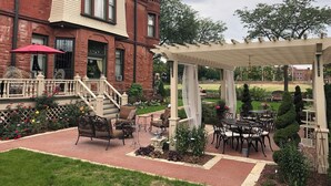 En murstensbygning med en overdækket patio med udendørs møbler og et pergola.