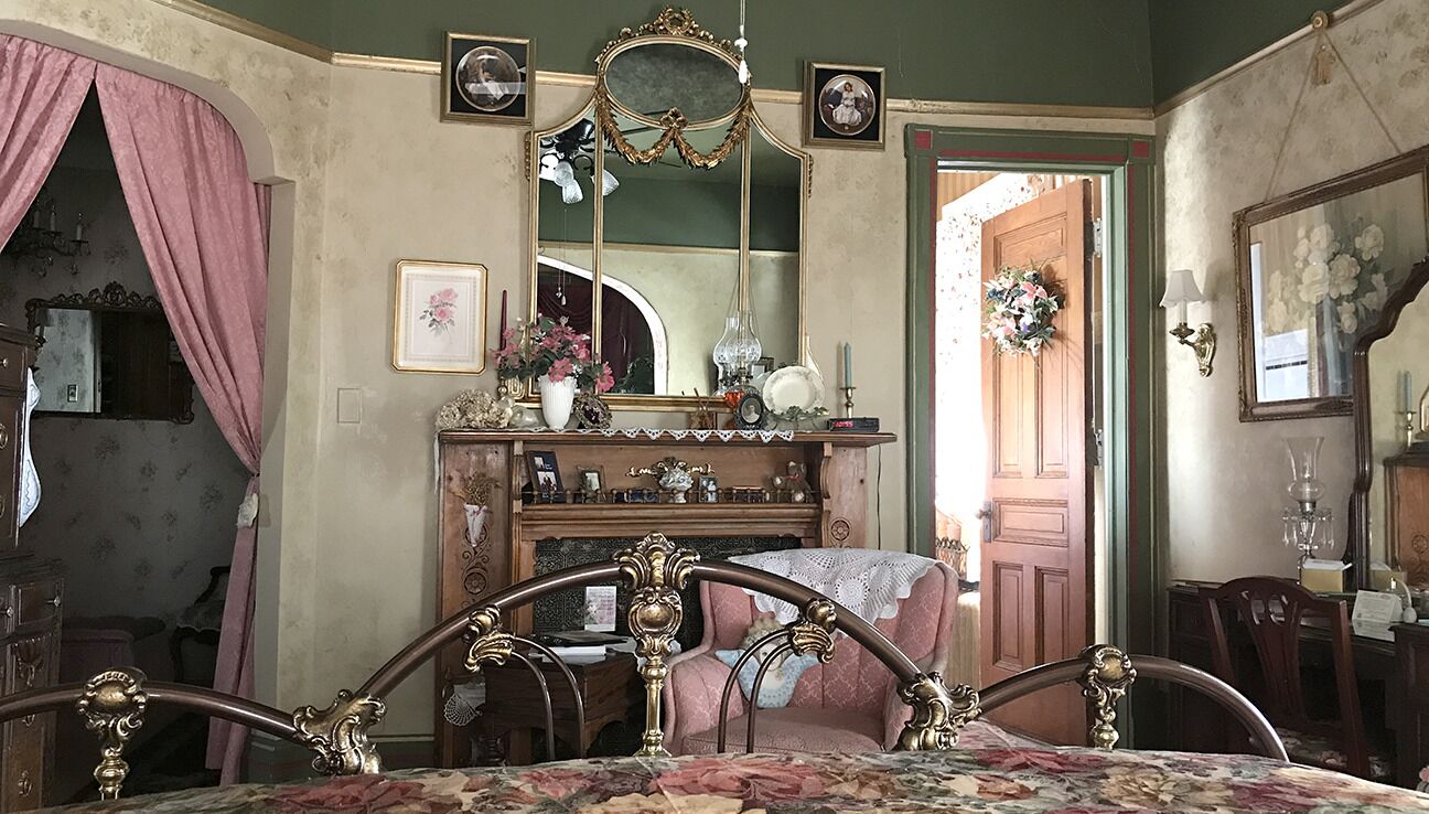 A room with a bed, a dresser, a mirror, and a door leading to another room.