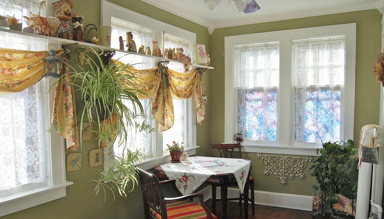 Un coin repas avec une table dressée pour deux personnes, entourée de chaises, et une fenêtre donnant sur l’extérieur.