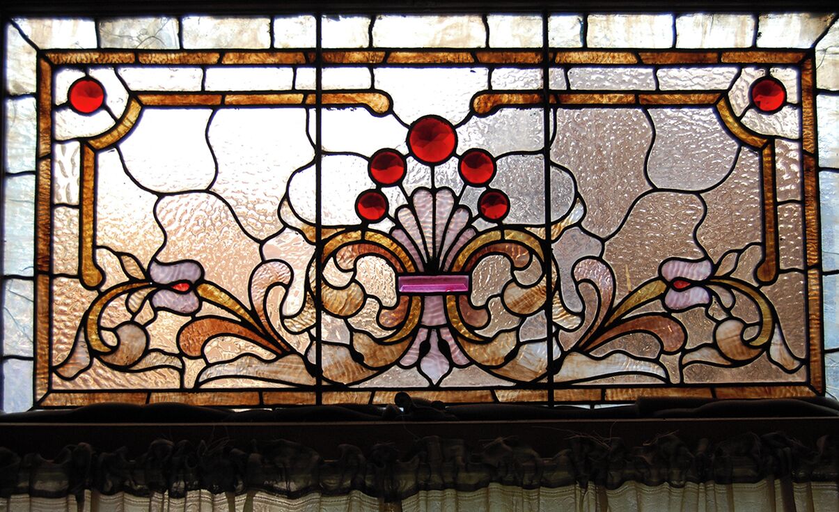 A stained glass window with a floral design and a central pink rectangle.