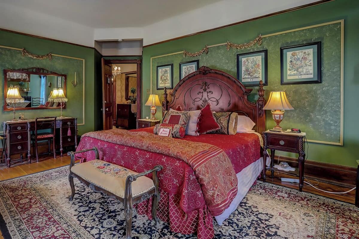 Un dormitorio tradicional con una cama grande, un aparador, un espejo y un banco.