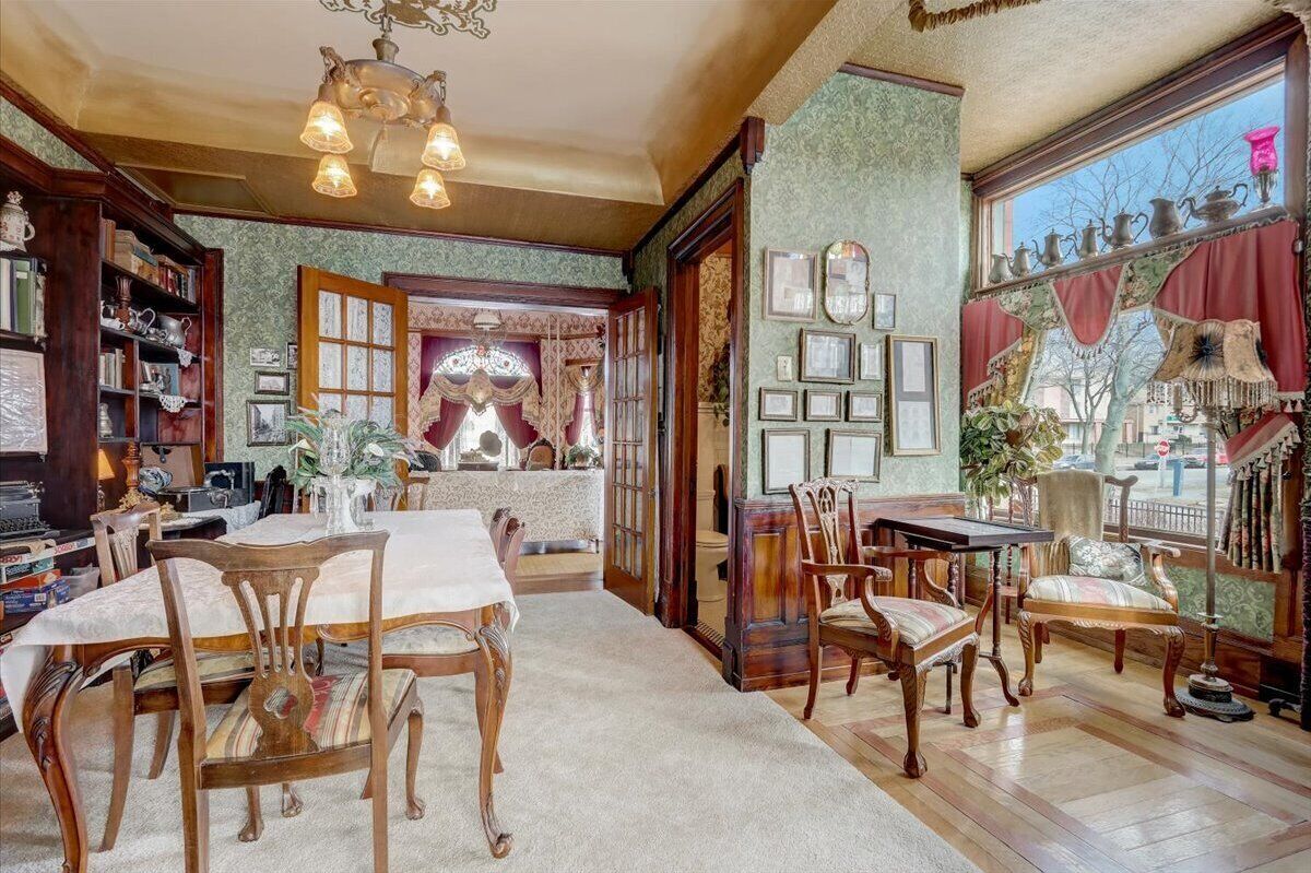 Ein geräumiges Zimmer mit Essbereich, Holzmöbeln und einem großen Fenster mit Dekoration.