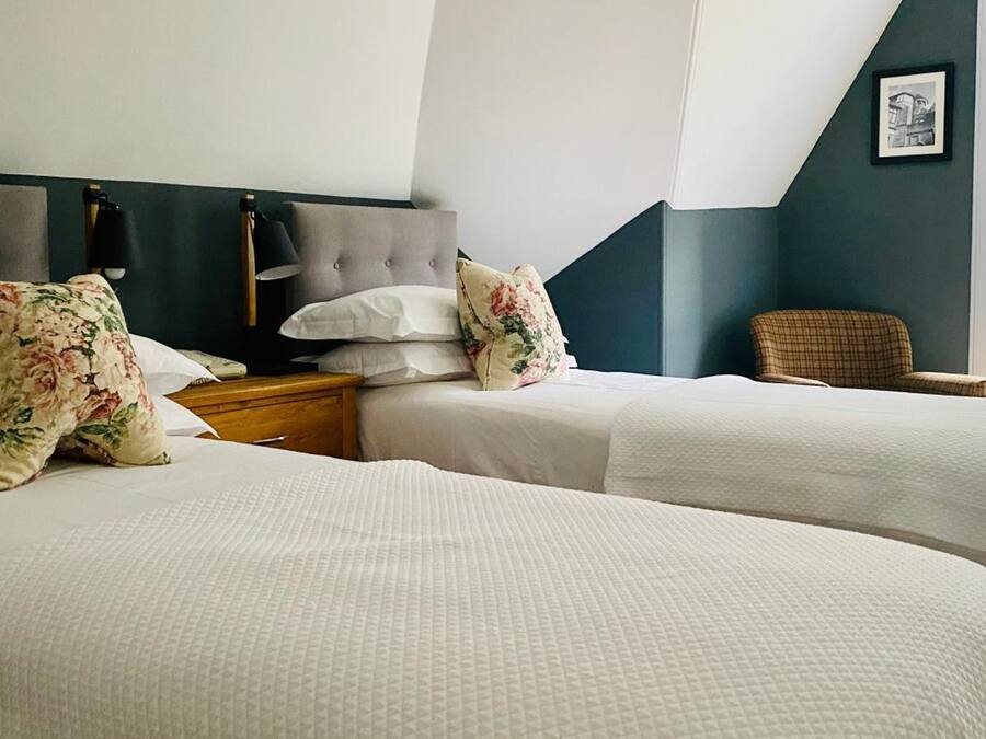 A hotel room with two beds, a nightstand, a chair, and a window with a view.