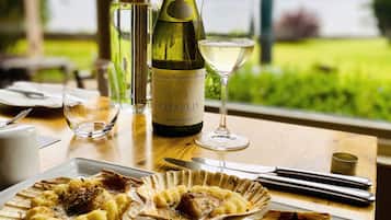 A dining table with a bottle of wine, a glass, and plates of food.