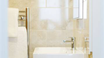 A modern bathroom with a white sink, a wooden vanity, and a glass shower enclosure.