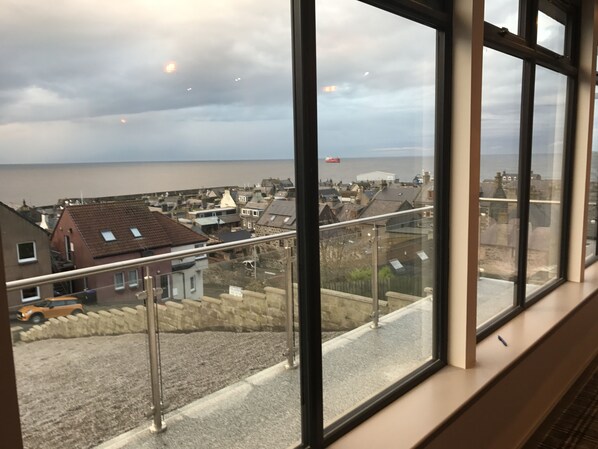 A view from a window overlooking a coastal town with houses and a body of water. - The Knowes Hotel & Restaurant (Macduff)