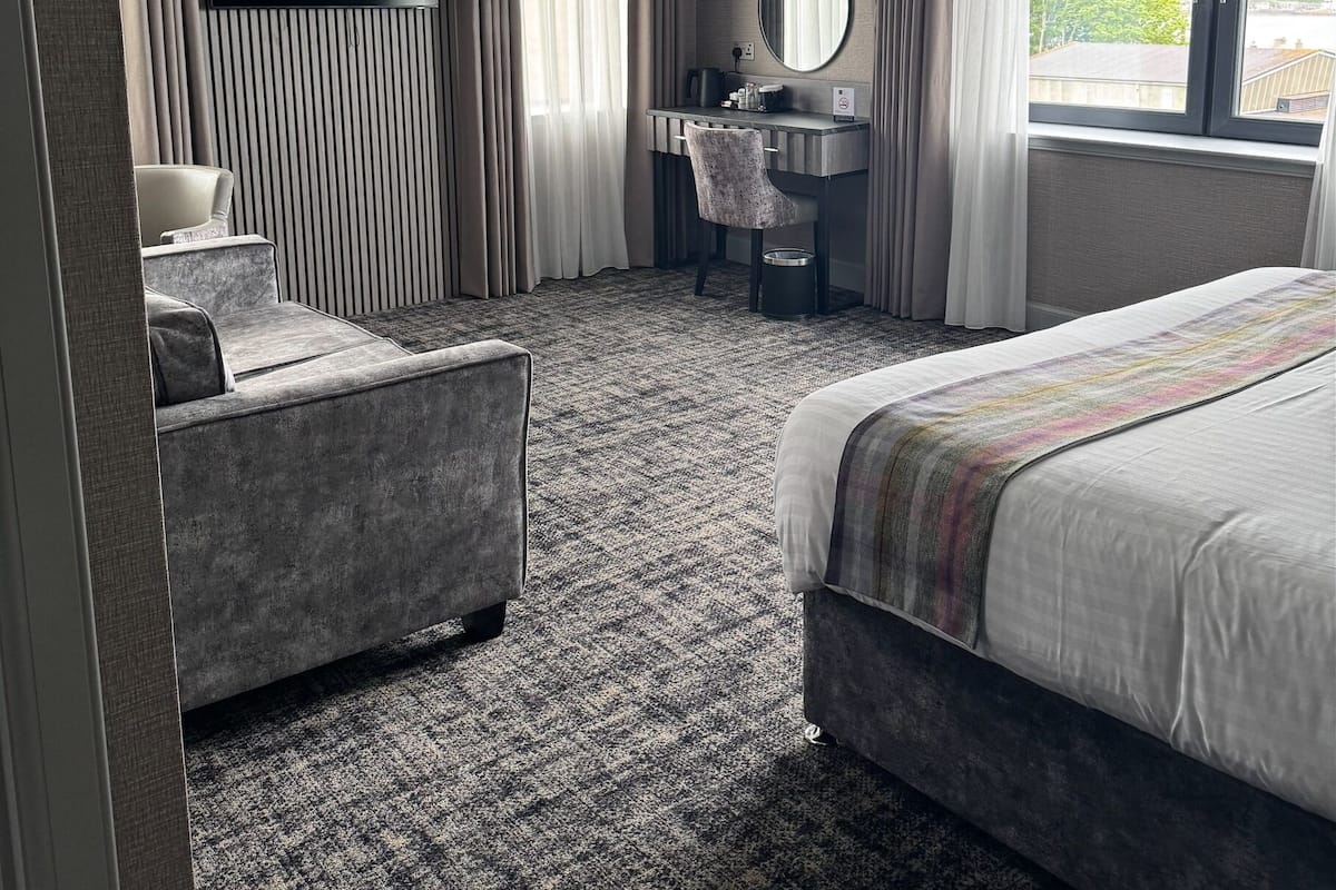A hotel room with a bed, a desk with a chair, a television, and a window with a view.