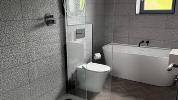 Une salle de bain moderne avec une douche à parois de verre, des toilettes et une baignoire sur pieds.