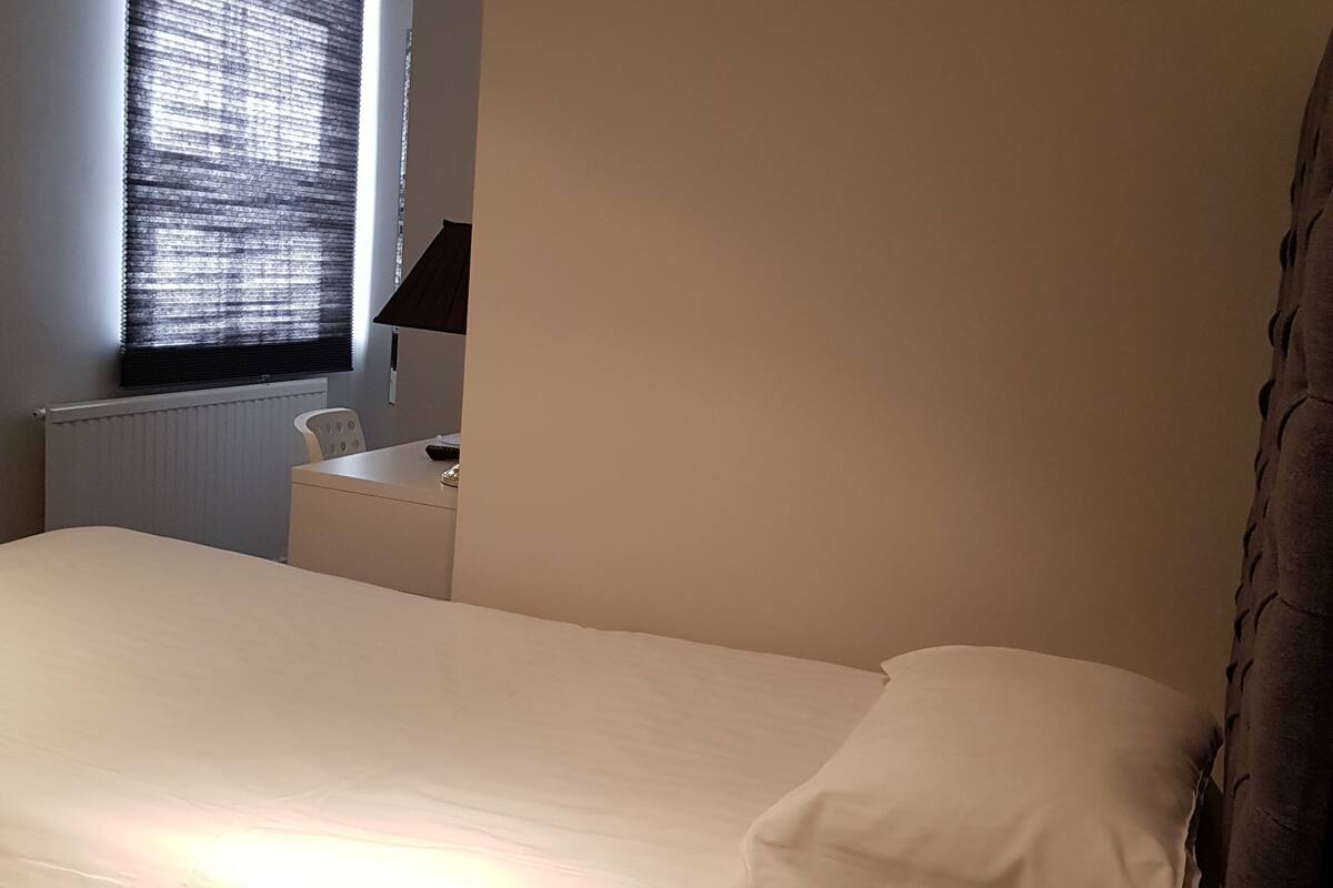 A bedroom with a bed, a desk, and a chair.