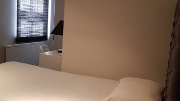A bedroom with a bed, a desk, and a chair.