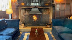 A cozy living room with a fireplace, two sofas, a coffee table, and wall sconces. - Mortons Manor (Wareham)