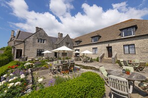 A stone building with outdoor seating and a garden. - Mortons Manor (Wareham)