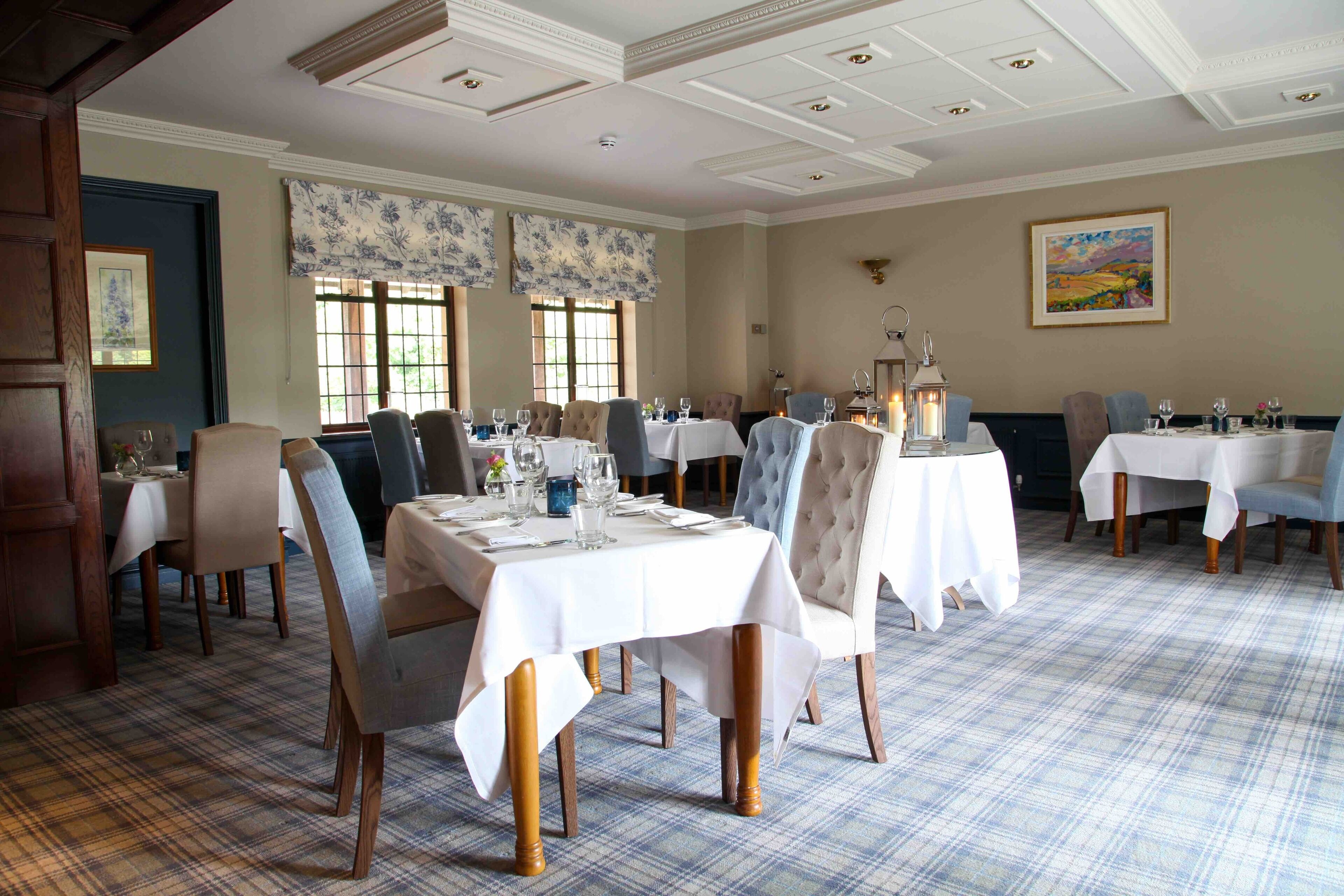 A dining area with multiple tables set for guests, featuring a checkered floor pattern and classic furniture.