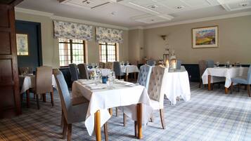 A dining area with multiple tables set for guests, featuring a checkered floor pattern and classic furniture.