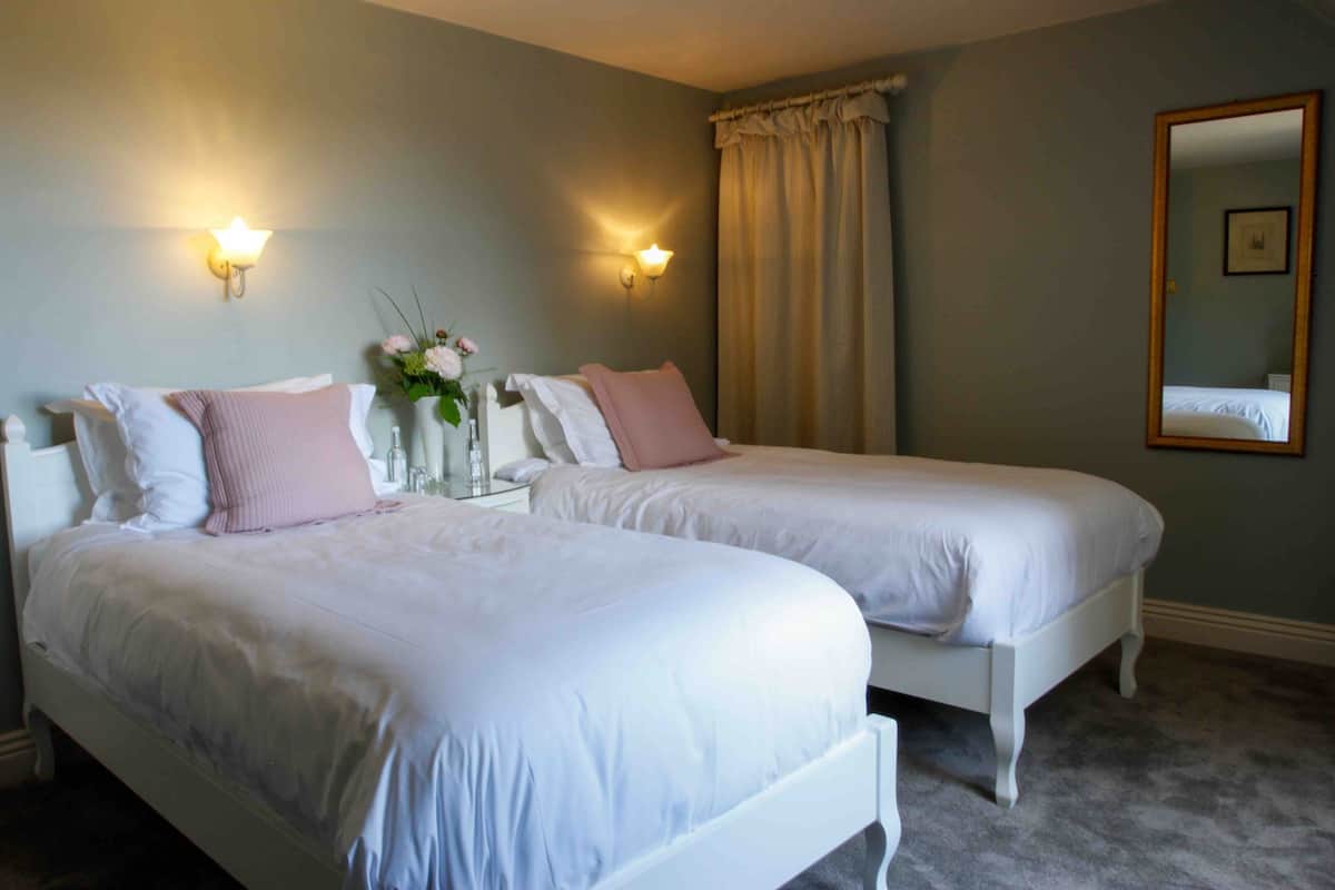 Quarto com duas camas, um espelho e luzes na parede.