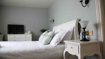 Ein Schlafzimmer mit einem Bett, einem Nachttisch, einer Lampe, einem Fernseher und Wandleuchten.