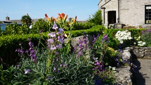 A stone building with a garden in front, featuring various flowers and a stone wall. - Mortons Manor (Wareham)