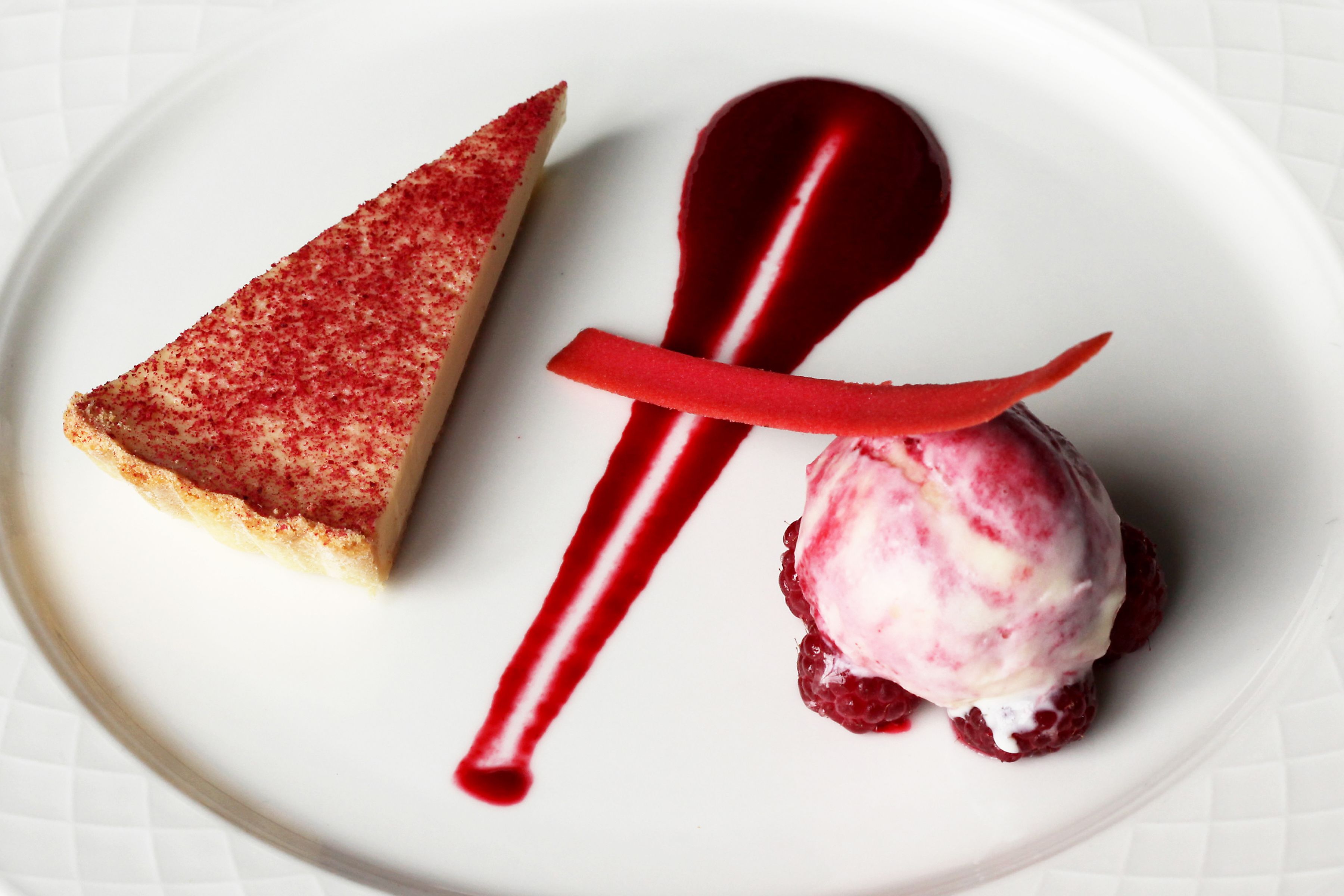 Un plat de postres amb una porció de pastís i una bola de gelat.