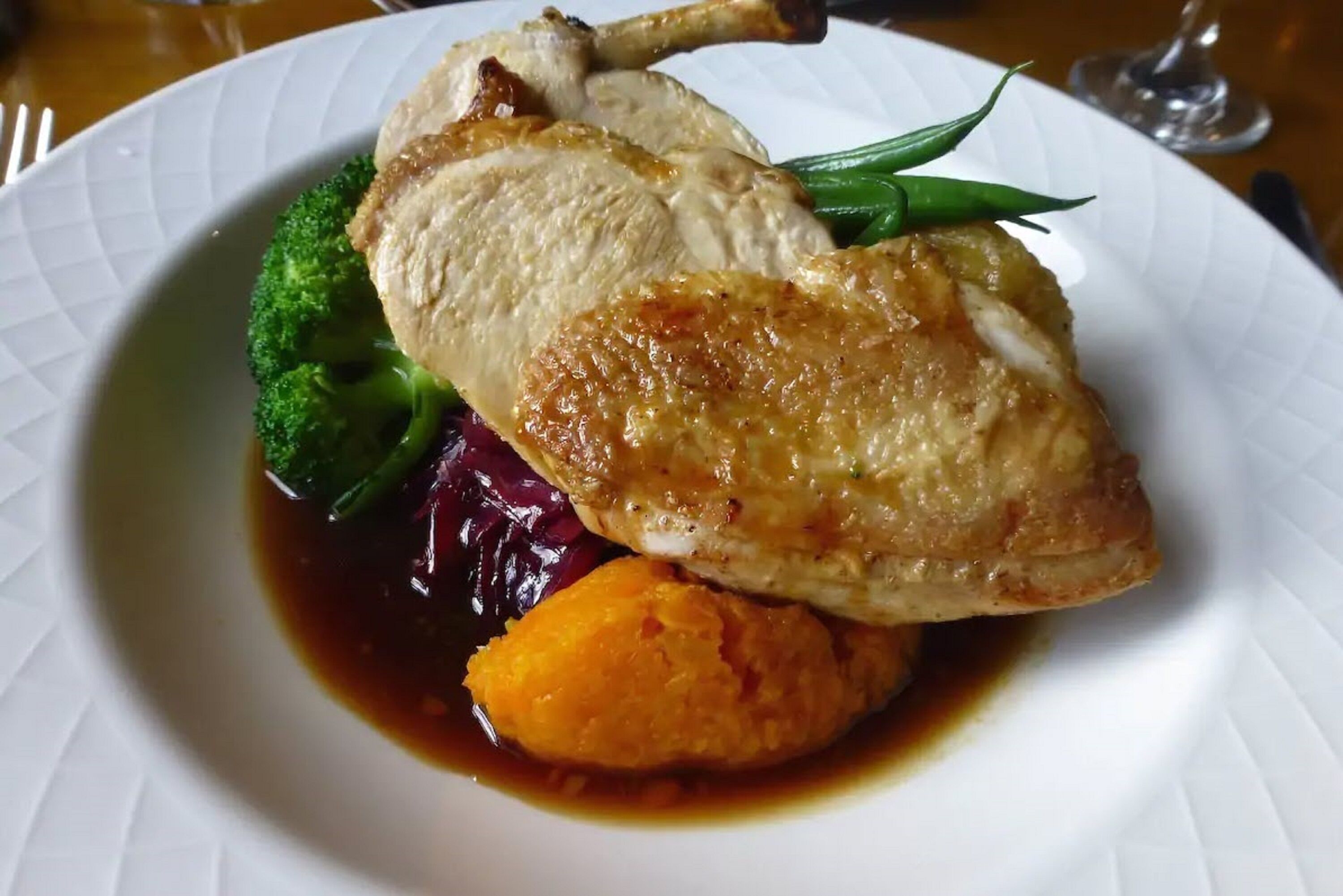 A plate with roasted chicken, broccoli, and purple cabbage.