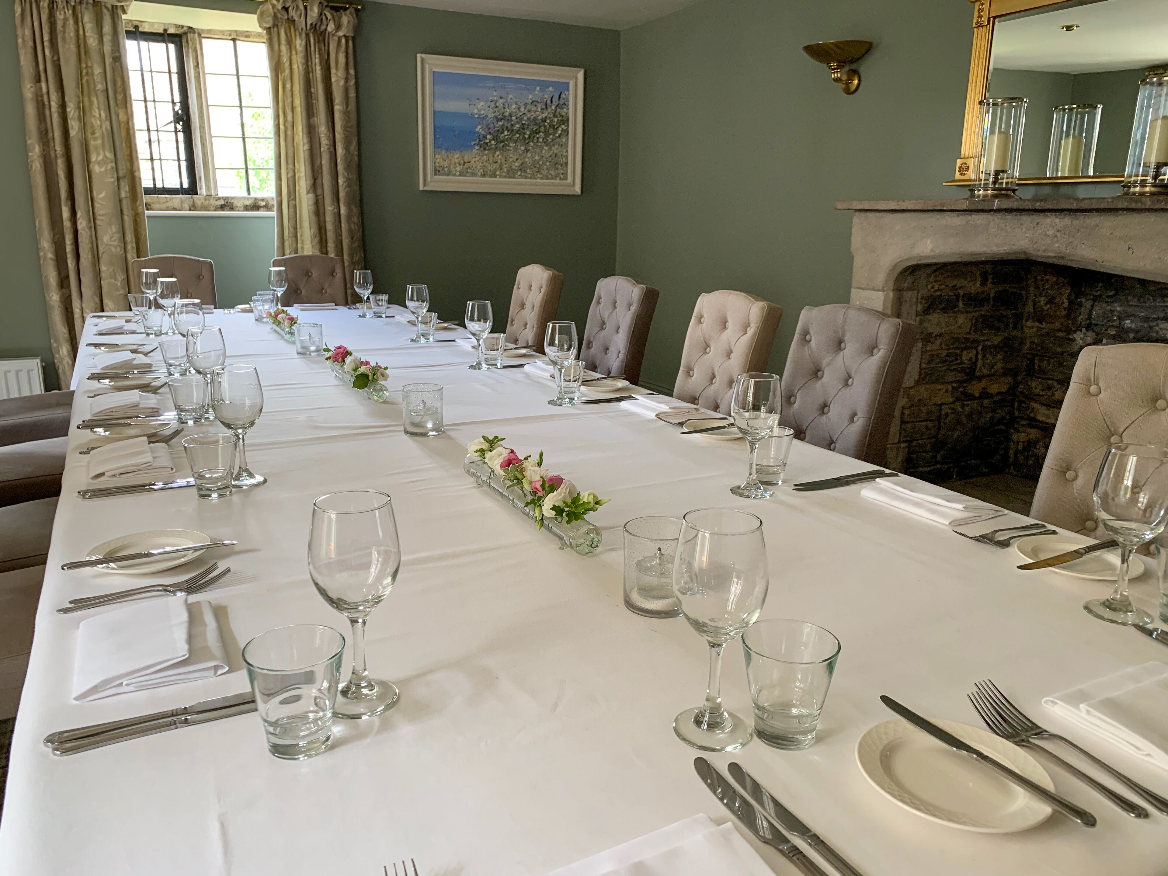 A long dining table set for a formal meal with chairs, glassware, and cutlery.