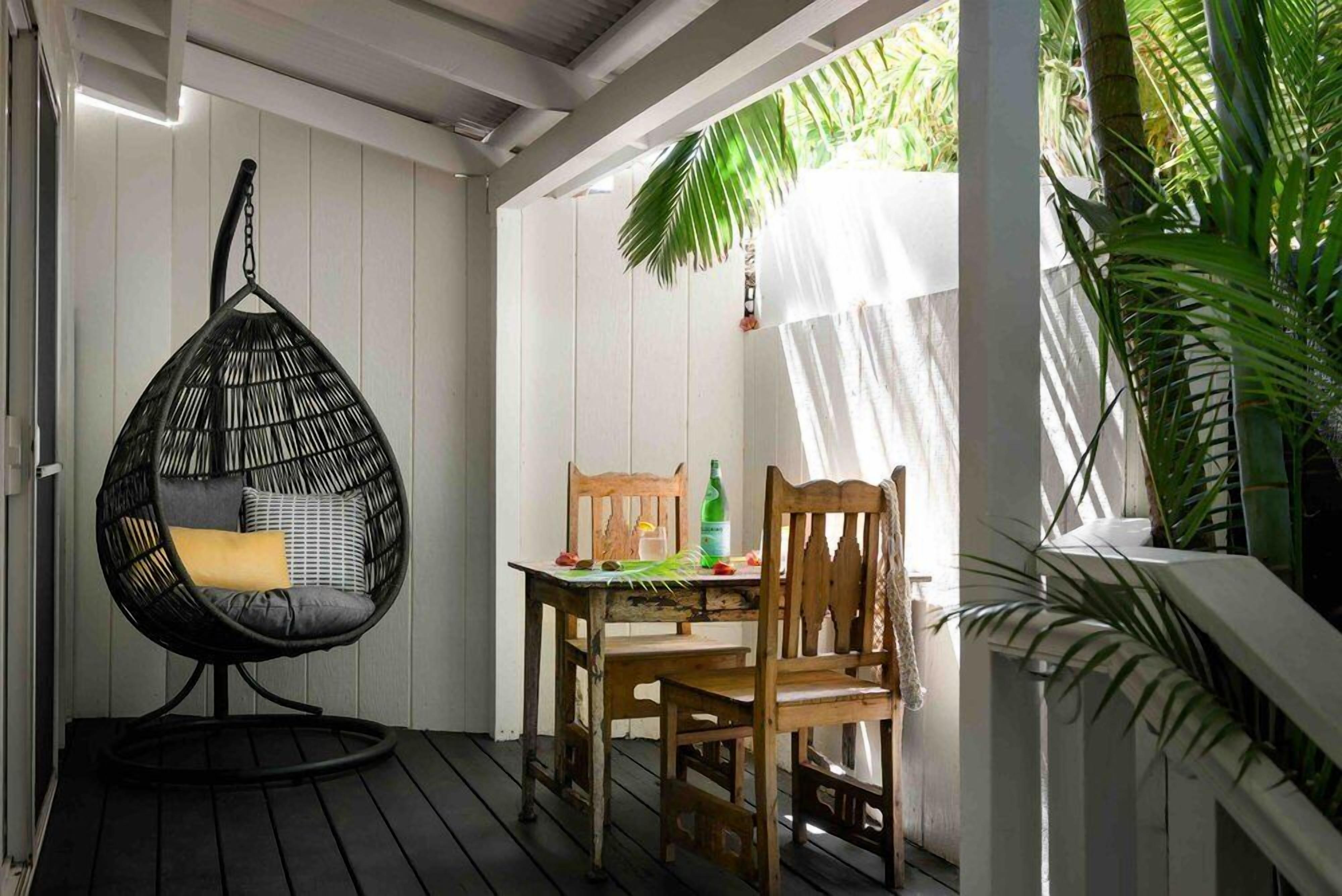 A cozy outdoor seating area with a hanging chair, a wooden table, and chairs.