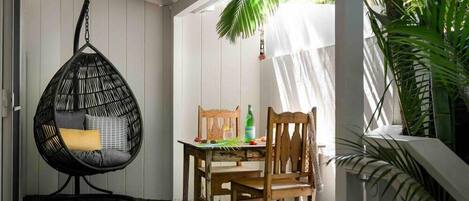 A cozy outdoor seating area with a hanging chair, a wooden table, and chairs.