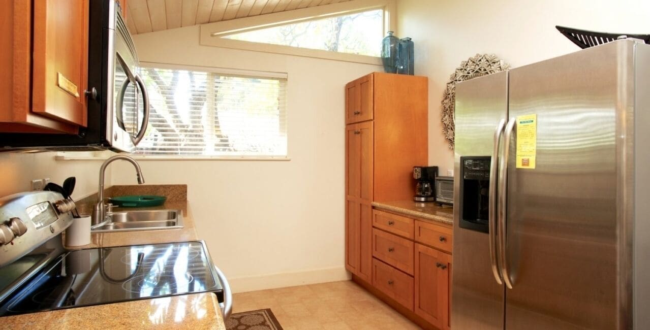 A kitchen with wooden cabinets, a stainless steel refrigerator, a microwave, and an oven.