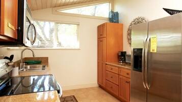 A kitchen with wooden cabinets, a stainless steel refrigerator, a microwave, and an oven.