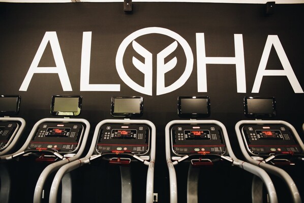 A fitness center with treadmills and a large logo on the wall.
