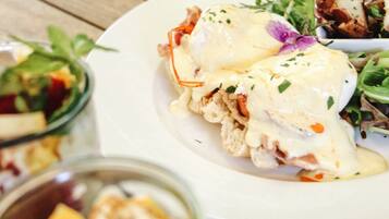 Un plato de comida con huevos benedictinos y una ensalada acompañante.