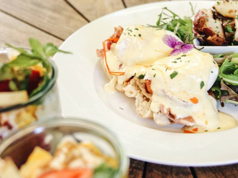 A plate of food with eggs benedict and a side salad.