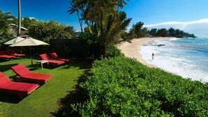 A beachside resort with red lounge chairs, a grassy lawn, and a view of the ocean. - Paia Inn (Paia)