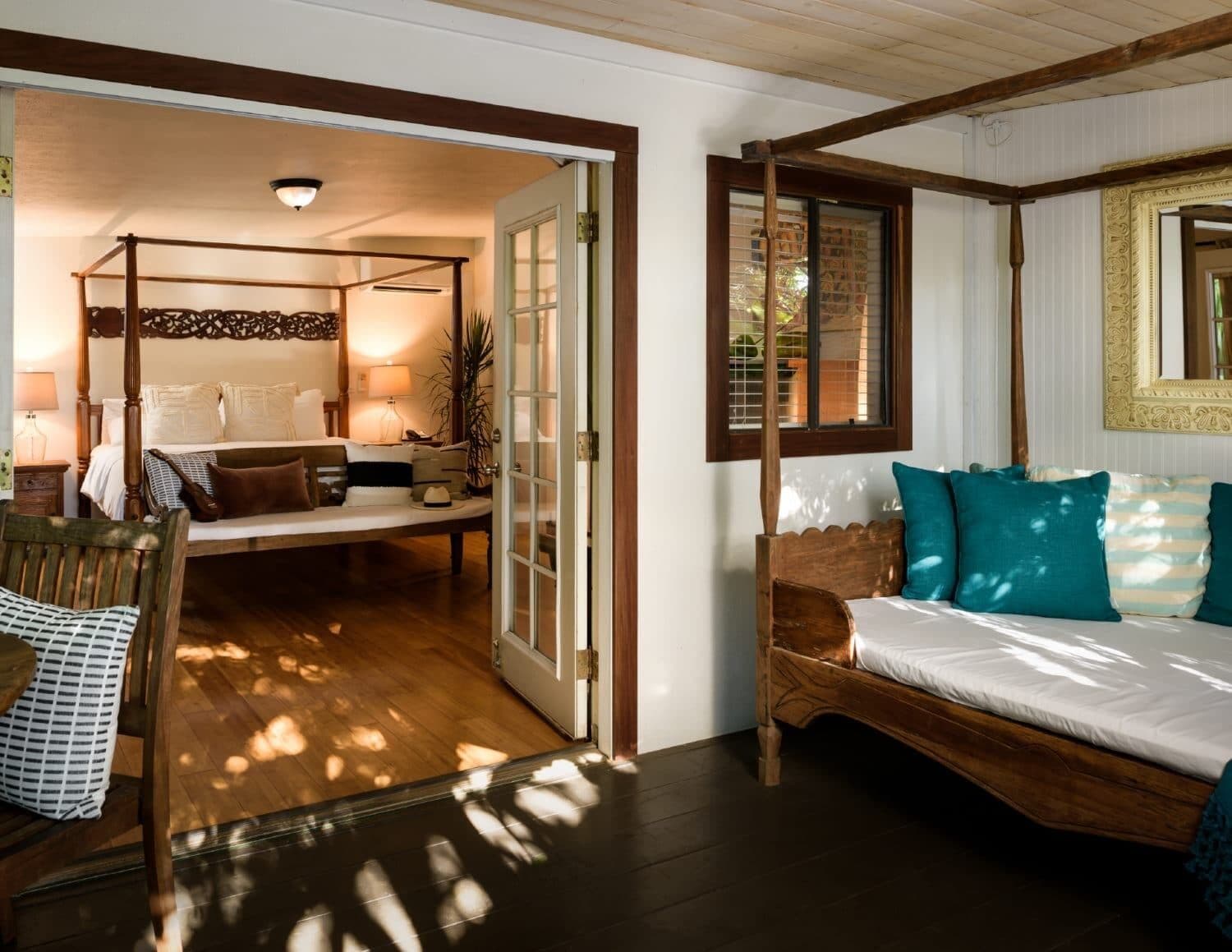 A bedroom with a four-poster bed, a daybed, and a wooden chair.