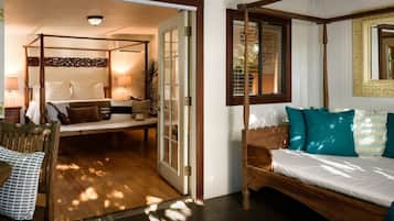 A bedroom with a four-poster bed, a daybed, and a wooden chair.