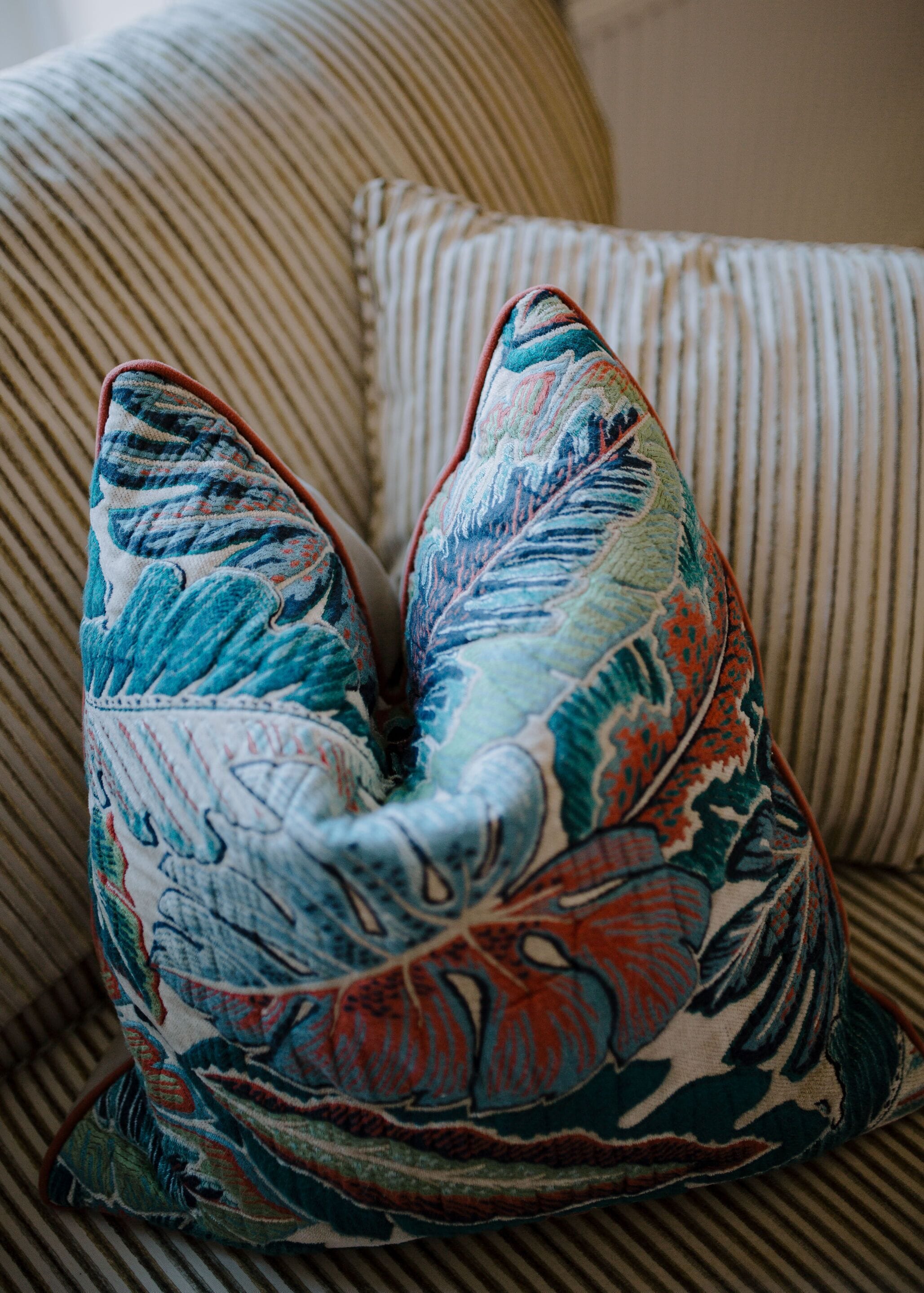 A striped sofa with a decorative pillow featuring a floral pattern.