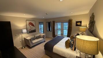 A modern hotel room with a large bed, a sofa, a desk, and a window with curtains.