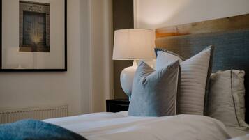 A hotel room with a neatly made bed, a lamp on a bedside table, and a framed picture on the wall.