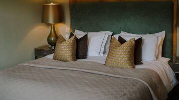A neatly made bed with a green headboard, a bedside lamp, and patterned pillows.